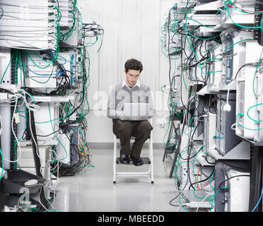 Caucasian male technician working on computer servers in a computer server farm. Stock Photo
