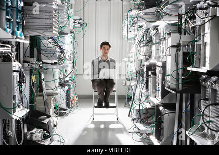 Caucasian male technician working on computer servers in a computer server farm. Stock Photo