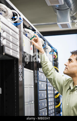 Male computer technician working on servers in a computer server farm. Stock Photo