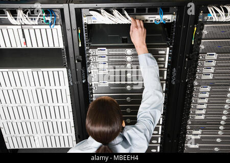 Caucasian woman lab technician working on servers in a computer sever farm. Stock Photo