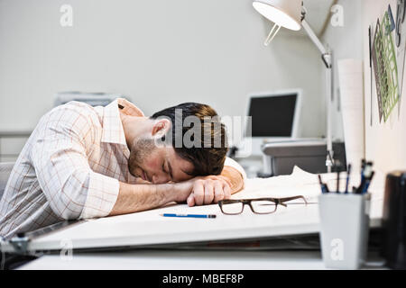 Hispanic man taking a quick nap in an architect's office. Stock Photo