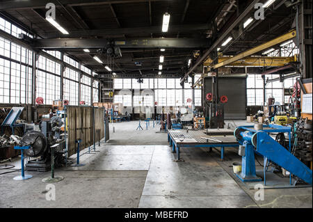 A factory floor with industrial machinery and open space, metal presses and overhead lifting gear and gantries. Production. Stock Photo