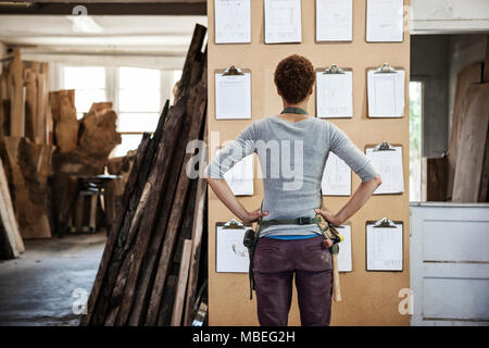 Woman factory worker checking project inventory in a woodworking factory. Stock Photo