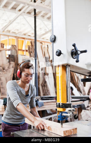 Black woman factory worker using a band saw to cut wood in a woodworking factory. Stock Photo