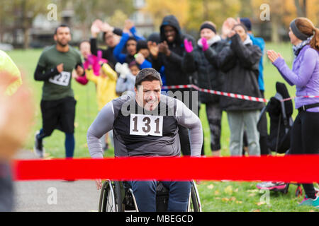 Determined man in wheelchair nearing charity race finish line in park Stock Photo