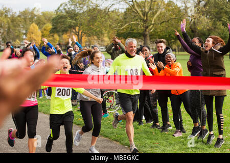 Enthusiastic family running, nearing charity run finish line in park Stock Photo