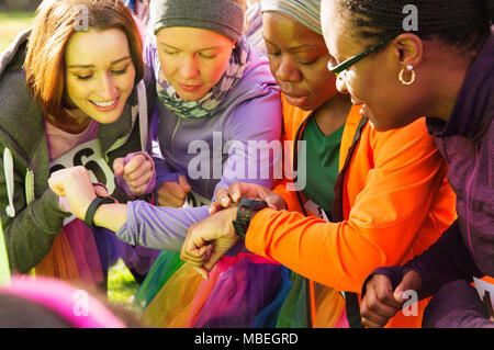 Female runners checking smart watches at charity run Stock Photo