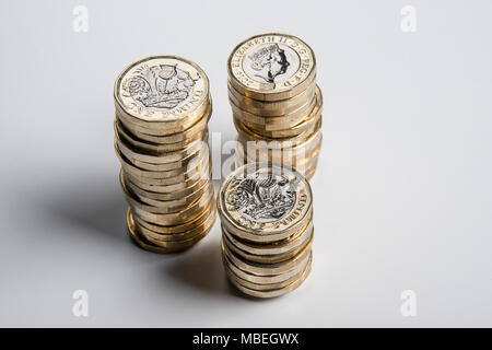 Three uneven piles of £1 coins, photographed from above. Stock Photo