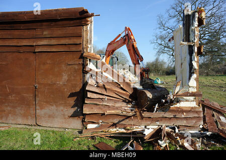 A large digger being used to demolish an old wooden barn. Stock Photo