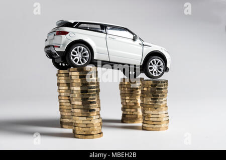 A toy Land Rover Evoque balanced on piles of £1 coins. Stock Photo