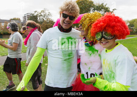 Portrait playful runners in wigs and holi powder at charity run in park Stock Photo