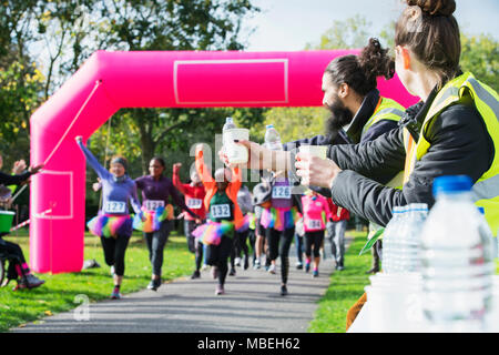 Volunteers with water ready for charity run runners crossing finish line Stock Photo