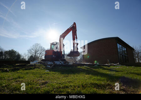 A large digger being used to demolish an old wooden barn. Stock Photo