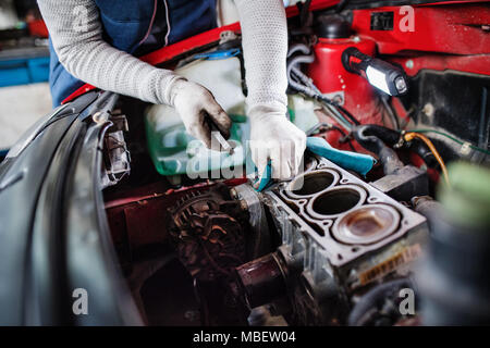 Unrecognizable man mechanic repairing a car in a garage. Stock Photo