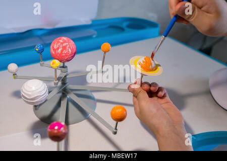 kid painting the Saturn on a Solar System model Stock Photo