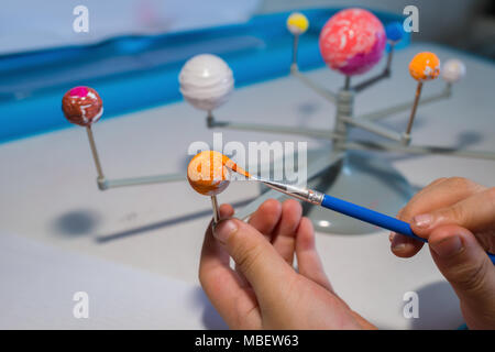 kid painting the Uranus on a Solar System model Stock Photo