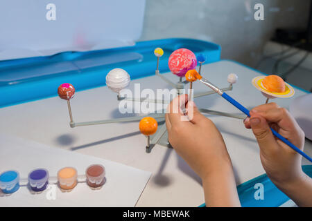 kid painting the Earth on a Solar System model Stock Photo