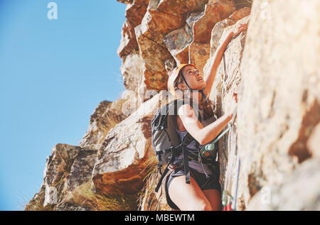 Focused, determined female rock climber scaling rock Stock Photo