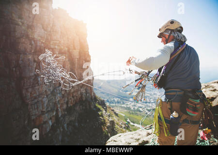 Male rock climber throwing rope Stock Photo