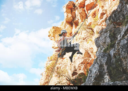 Female rock climber descending rocks Stock Photo