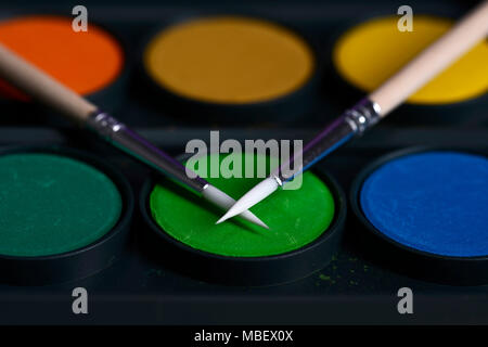 two thin brushes lie on colorful paints for drawing close-ups Stock Photo