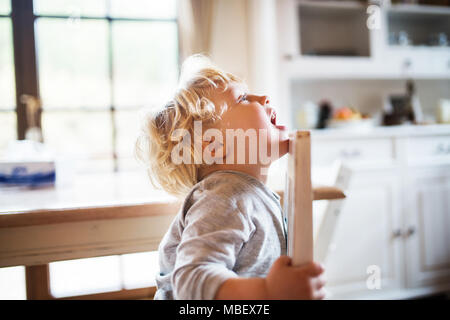 A toddler boy sitting at the table at home. Stock Photo