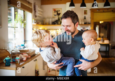 Father holding two toddlers at home. Paternity leave. Stock Photo