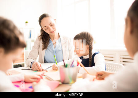 Teacher helping students during art class in school classroom Stock Photo