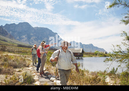 Active senior friends hiking and enjoying sunny summer lake view Stock Photo