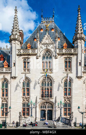 Tourists resting on the steps of the Provincial Court, Provincaal Hof in the Grote Markt or Market Square, Bruges (Brugge), Belgium Stock Photo