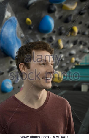 Portrait smiling male rock climber at climbing wall in climbing gym