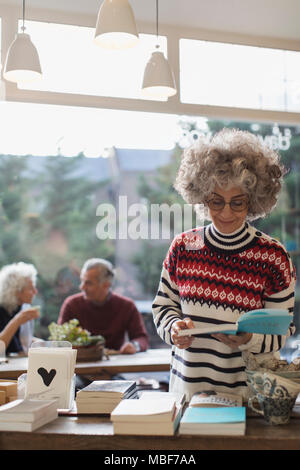 Senior woman reading book in shop Stock Photo