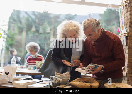 Senior couple looking at book in shop Stock Photo
