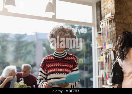 Portrait smiling senior woman reading book in shop Stock Photo