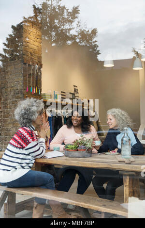 Women friends drinking tea in cafe shop window Stock Photo
