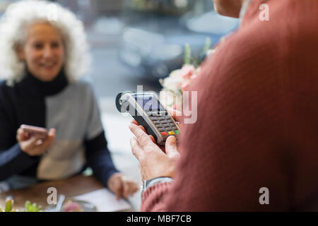 Cashier with credit card machine ready for contactless payment Stock Photo