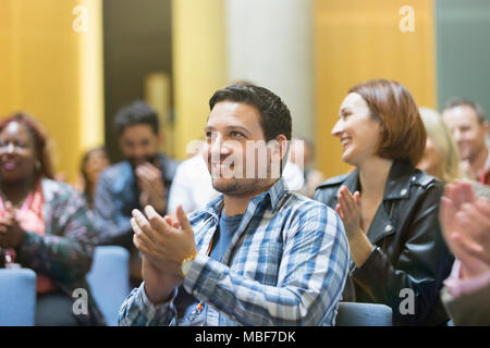 Smiling man clapping in conference audience Stock Photo