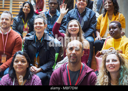 Woman participating, raising hand in conference audience Stock Photo