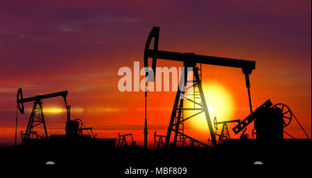 Oil pumps silhouettes working on clouds and sun in background. Pumpjack on oilfield on sunset. Concept of oil rig, global warming, environment polluti Stock Photo