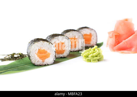 Delicious fresh mini-rolls with salmon on a banana leaf. Sushi rolls on a white background with ginger and wasabi. The Japanese menu. Stock Photo