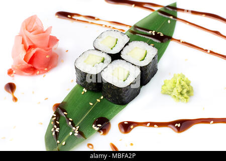 Delicious fresh mini-rolls with cucumber on a banana leaf. Sushi rolls on a white background with ginger and wasabi. The Japanese menu. Stock Photo
