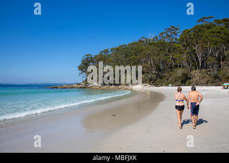 Couple walking along the white sands of Blenheim beach in Jervis Bay, national park, blue sky and white sand, Australia Stock Photo