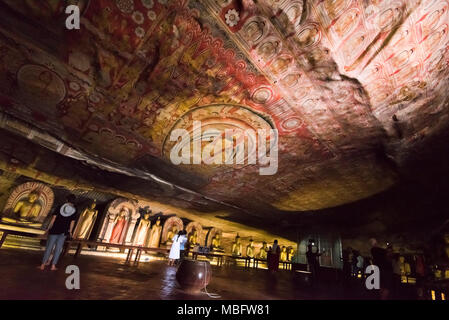Horizontal view of tourists walking around the Cave of the Great Kings in the Dambulla Cave Temple in Sri Lanka. Stock Photo