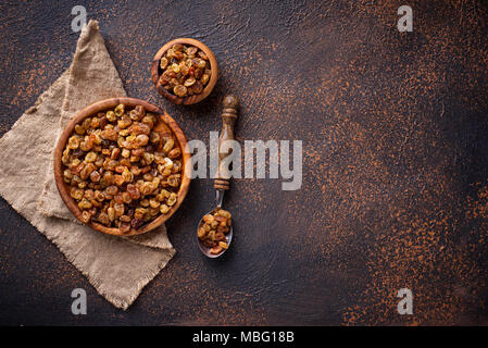 Raisins in wooden bowl on rusty background Stock Photo