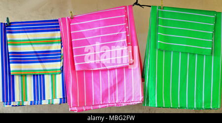 Colorist fabric bed sheets and pillowcases fixed by plastic clothes pegs hanging from a clothes line for sale in a stall of the City Public Market-Sip Stock Photo