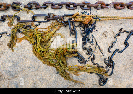Some old discarded ropes, chains and lines with shackles from an old boat on a sandy beach making and abstract or interesting pattern or design. Coast Stock Photo