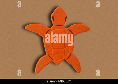 A orange turtle  rubber eva on painted background imitating sand Stock Photo