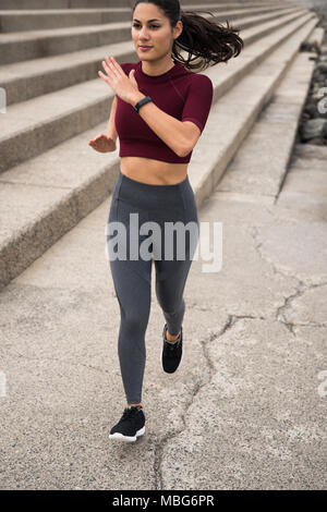 Sporty brunette running next to stairs 