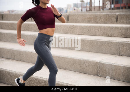 Young woman running along the promenade in tights and 3/4 shirt wearing a black watch Stock Photo