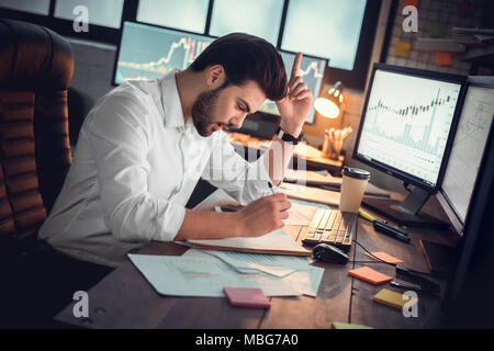 Excited motivated businessman got new business idea writing notes about project startup, happy young trader investor raising finger found best solutio